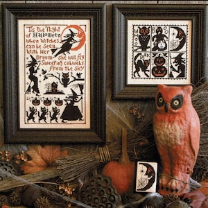 May include: Two framed cross-stitch patterns with a Halloween theme. The first pattern features a witch flying on a broom with the text "Tis the Night of Halloween When Witches can be seen. With Her Broom she will fly Sweeping cobwebs From the Sky". The second pattern features a black cat, an owl, a pumpkin, and a spider web.