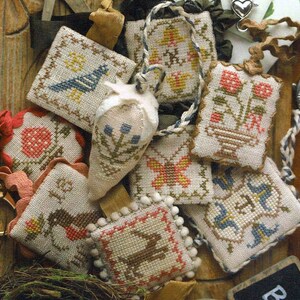 May include: A collection of nine small, hand-stitched fabric ornaments with various designs, including birds, flowers, butterflies, and strawberries. The ornaments are made in a variety of colors, including red, blue, green, yellow, and brown. They are all attached to a string or ribbon and would make a charming addition to any home decor.
