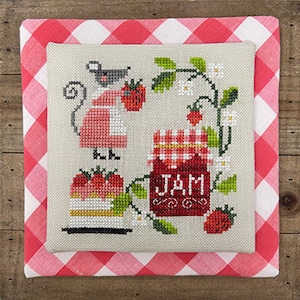 May include: Cross-stitch embroidery featuring a mouse in a red apron holding a strawberry, a jar of jam, and a strawberry cake. The design is set against a beige background and framed by a red and white gingham pattern.