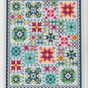 May include: A framed cross-stitch sampler featuring a grid of geometric patterns in shades of teal, magenta, yellow, and green. The design includes star-shaped motifs, small squares, and intricate borders on a white fabric background.