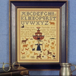 May include: A framed cross-stitch design featuring the alphabet, a depiction of Noah's Ark, and a verse from the Bible: "You are female and to bring into the ark two of all living creatures male to keep them alive with you. Gen. 6.19".