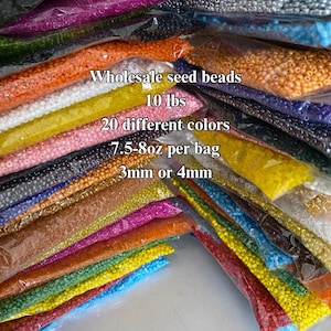 May include: A large stack of small plastic bags filled with colorful seed beads. The bags are labeled "Wholesale seed beads 10 lbs 20 different colors 7.5-8oz per bag 3mm or 4mm".