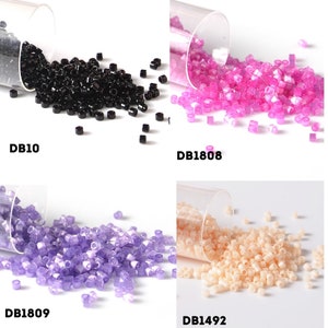 Peut inclure: Quatre contenants de perles de rocaille, chacun d'une couleur différente. Les couleurs sont le noir, le rose, le violet et le beige. Les contenants sont étiquetés avec les codes suivants : DB10, DB1808, DB1809 et DB1492.