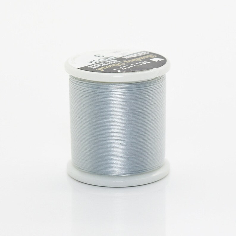 May include: A spool of silver thread with the text "Miyuki  Beading Thread  Size C  100% Polyester  Made in Japan" on the label.