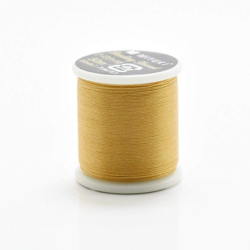 May include: A spool of gold thread with the text "MIYUKI" and "Polyester Thread" on the label.