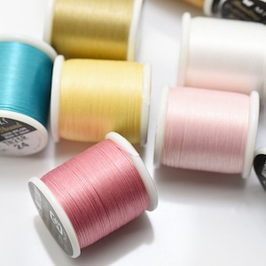 May include: Assortment of spools of embroidery thread in various colors, including teal, yellow, pink, and blue. The spools are labeled "Miyuki Beading Thread".