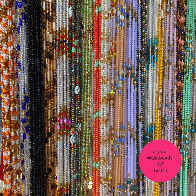 May include: A selection of colourful crystal waistbeads in shades of orange, black, white, green, and purple. The image includes a pink circle with the text "crystal Waistbeads 45" Tie On."