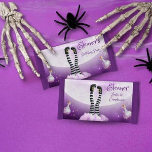 May include: Two purple candy bar wrappers with witch legs, text "Eleanor's Birthday Party" and "Fiesta de Cumpleaños". The wrappers feature a witch leg design, a potion bottle, and a spider web. Skeleton hands and black spiders are scattered around.
