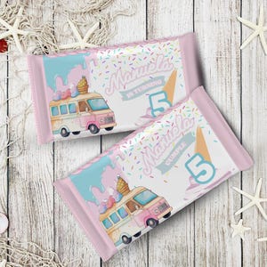 Puede incluir: Dos envoltorios de barras de caramelo rosas con un diseño de camión de helados colorido. Los envoltorios presentan el nombre "Manuela" y el número "5", con el texto "CUMPLE" y un patrón de chispas.