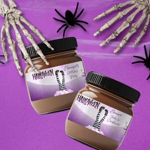 May include: Two glass jars with black lids filled with a brown substance, labeled "Halloween" and "Eleanor's Birthday Party." The labels feature witch legs and a purple background. Skeleton hands and black spiders are scattered around.