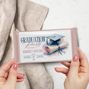 May include: A pink graduation party invitation with a watercolour design. The invitation features a graduation cap, diploma, and event details, including the name Kimberly Gostanza, date, and time.