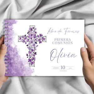 Puede incluir: Un libro de firmas con espiral con un diseño de acuarela púrpura. La portada presenta una cruz floral y las palabras "Libro de Firmas" y "Primera Comunión" con el nombre "Olivia" y la fecha.
