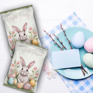 Puede incluir: Dos bolsas de regalo blancas con ilustraciones de conejos y huevos de Pascua de colores pastel. Las bolsas están decoradas con flores rosas y hojas verdes. El texto en las bolsas dice "Easter Party" y "Fiesta de Pascua".