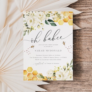 May include: A baby shower invitation featuring a watercolour illustration of white flowers and a honeycomb pattern. The text reads "oh babee" and includes the event details: "Join us for a baby shower in honour of Sarah McDonald, Saturday August 28th at 2:00pm, The Stables Inn, 17564 N Maple Drive, IL 47563, RSVP to Courtney 000.000.0000, registered at Target & Amazon."