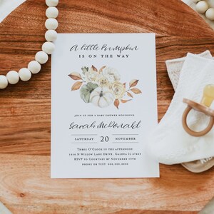 May include: A baby shower invitation with a fall theme. The invitation features a watercolor illustration of pumpkins, leaves, and flowers. The text on the invitation reads "A little pumpkin is on the way" and "Join us for a baby shower honoring Sarah McDonald". The invitation also includes the date, time, and location of the shower.