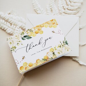 May include: White thank you card featuring a watercolour floral design and a honeycomb pattern. The card reads "Thank you" in cursive and "Love, The McDonalds" in print.