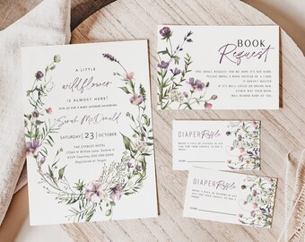 Puede incluir: Una invitación a una fiesta de bienvenida al bebé con un diseño de corona floral de acuarela. La invitación dice "A Little Wildflower is Almost Here!" e incluye la fecha, la hora y el lugar del evento. La invitación también incluye una tarjeta de solicitud de libro y dos tarjetas de rifa de pañales.