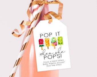 May include: White gift tag with the text "POP IT when she POPS!" and a graphic of colorful popsicles. The text below the popsicles reads "Enjoy a toast when Baby Adams arrives! Due Sep 2022."