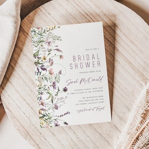 May include: A white card with purple text announcing a bridal shower for Sarah McDonald. The card is decorated with a watercolor floral border. The text reads "Save the Date for a Bridal Shower Honoring Bride-to-Be Sarah McDonald Saturday August 12th 2023 at three o'clock in the afternoon The McDonald House 1114 North Willow Lane San Antonio, Texas Registered at Target"