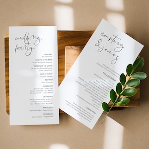 Op de afbeelding: Huwelijksceremonieprogramma met een witte achtergrond en zwarte tekst. Het programma geeft de volgorde van de gebeurtenissen weer, inclusief de processie, lezingen, geloften en receptie. Het programma bevat ook de namen van de leden van de bruiloftspartij.