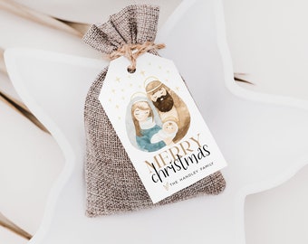 Può includere: Un'etichetta regalo bianca con un'illustrazione ad acquerello della Sacra Famiglia. L'etichetta ha una scritta dorata che recita "Buon Natale" e "The Hadley Family".