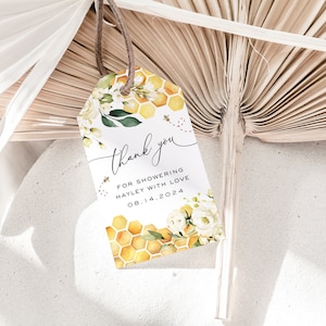 May include: A white thank you tag with a beehive design and yellow and white flowers. The text reads "Thank you for showering Hayley with love 08.14.2024".