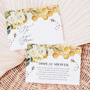 May include: Two white cards with a watercolour design of white flowers, yellow honeycomb, and bees. The top card says "To: From:" and the bottom card says "Display Shower" with instructions for guests to bring unwrapped gifts.
