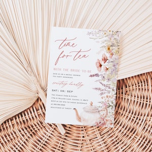 Könnte beinhalten: Eine weiße Einladungskarte mit einem Aquarell-Blumenmuster und einer Teekannen-Illustration. Der Text lautet "Time for tea with the bride-to-be" und enthält Details für eine Brautdusche-Teeparty zu Ehren von "Courtney Hardly" am Samstag, den 9. September.