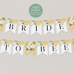 May include: White and yellow bridal banner with the text "Bride to Bee" and a floral design. The banner is made of paper and has a honeycomb pattern.