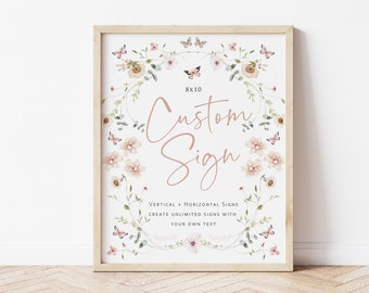 Op de afbeelding: Een printbaar bord van 20,3 x 25,4 cm met een bloemkransrand en vlinders. Het bord zegt "Custom Sign" en "Vertical + Horizontal Signs Create Unlimited Signs with Your Own Text".