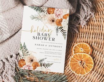 May include: A white baby shower invitation with gold lettering that reads "holiday baby shower" and features a floral design with dried oranges and ferns. The invitation includes the names "Sarah & Anthony", the date "Saturday, December 13th, 2021", the time "3:00pm", the location "The McDonald Residence", the address "1465 N Willow Lane Garden, White", and the RSVP information "RSVP Sarah 000-000-0000".
