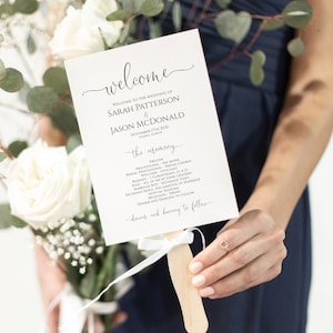 May include: A white wedding program fan with black text. The program lists the order of the ceremony, including the processional, readings, and vows. The text at the top reads "Welcome to the wedding of Sarah Patterson & Jason McDonald".