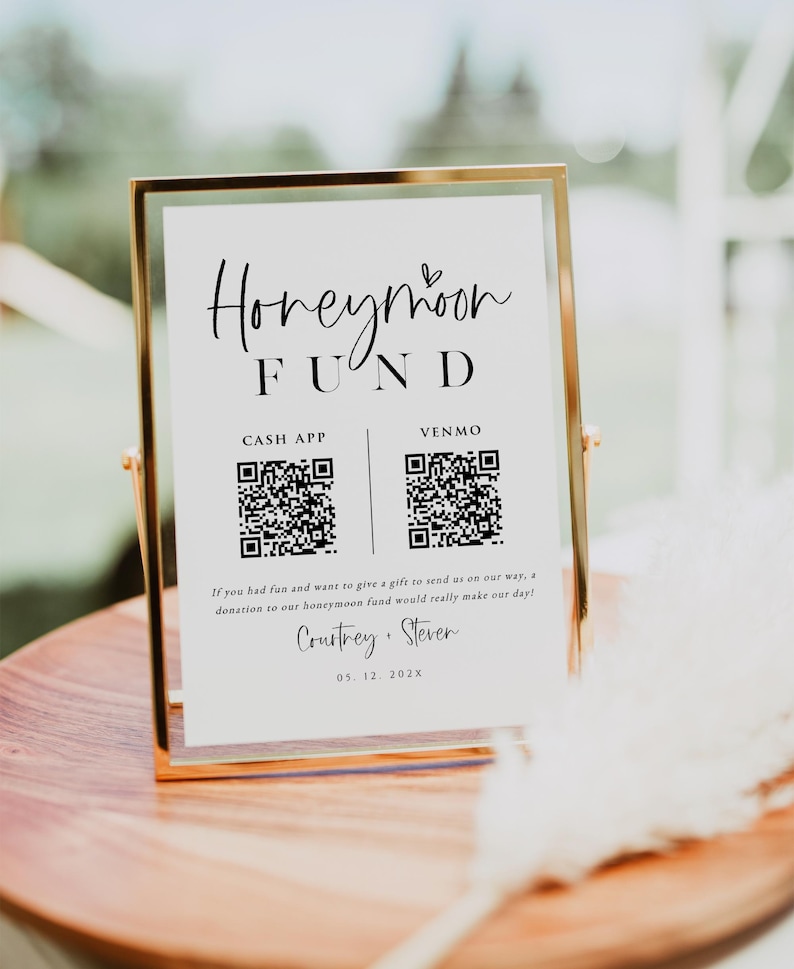 May include: A white sign with black text and a heart symbol reads "Honeymoon Fund".  The sign has two QR codes, one for Cash App and one for Venmo.  The sign also includes the names "Courtney & Steven" and the date "05. 12. 202X".