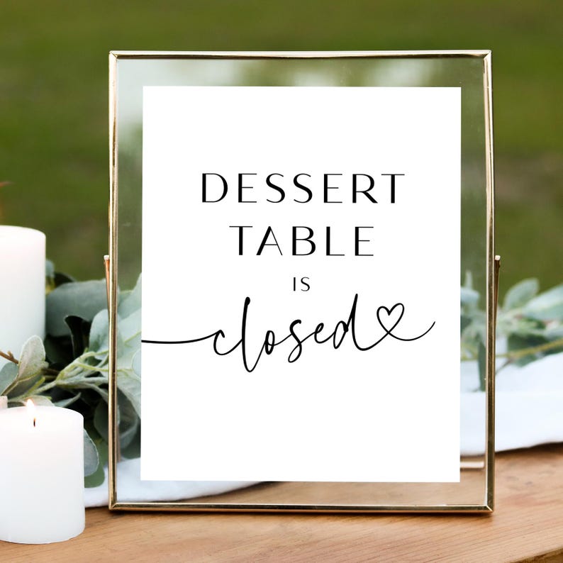 May include: A white sign with black text in a gold frame that reads "Dessert Table is closed" with a heart symbol.