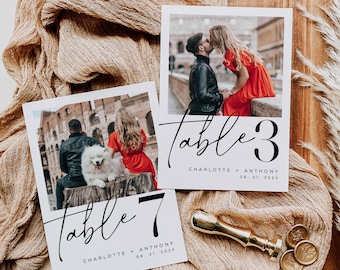 May include: Two wedding table number cards with photos of a couple. The table number cards are white with black calligraphy and numbers. The top card says "table 3" and the bottom card says "table 7". Both cards have the couple's names and wedding date.