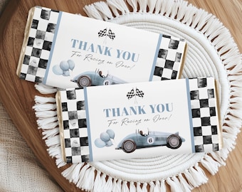 May include: Two chocolate bar wrappers with a racing theme. Each wrapper features a light blue race car, checkered flag, and the text "THANK YOU For Racing on Over!". The wrappers have a blue and black checkered pattern on the ends.