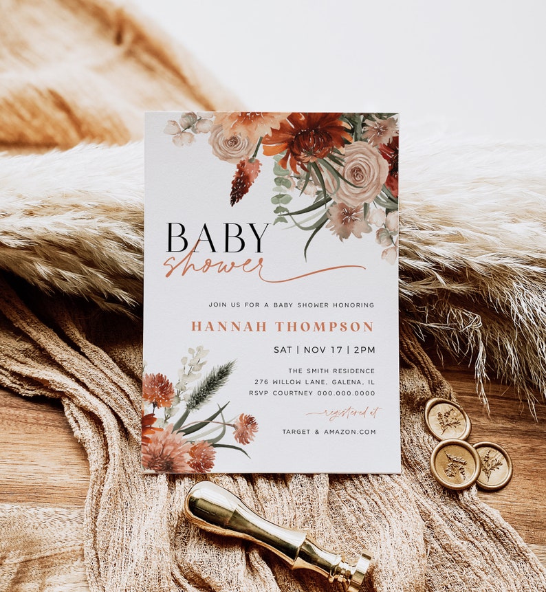 May include: A baby shower invitation with a floral design in shades of orange, pink, and green. The text reads "Baby Shower" and includes the name "Hannah Thompson", the date "Sat | Nov 17 | 2PM", the location "The Smith Residence", and the address "276 Willow Lane, Galena, IL".