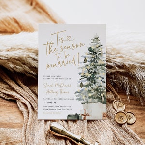 May include: A watercolor illustration of a Christmas tree with lights and ornaments. The text "Tis the season to be married!" is written in gold script. The invitation is for a wedding on December 10th at 3:00 PM at The Stables Inn and Suites in Galena, Illinois.