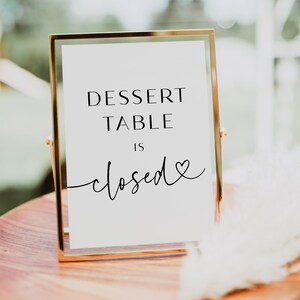 May include: A gold-framed sign with the text "Dessert Table is closed" with a small heart symbol.