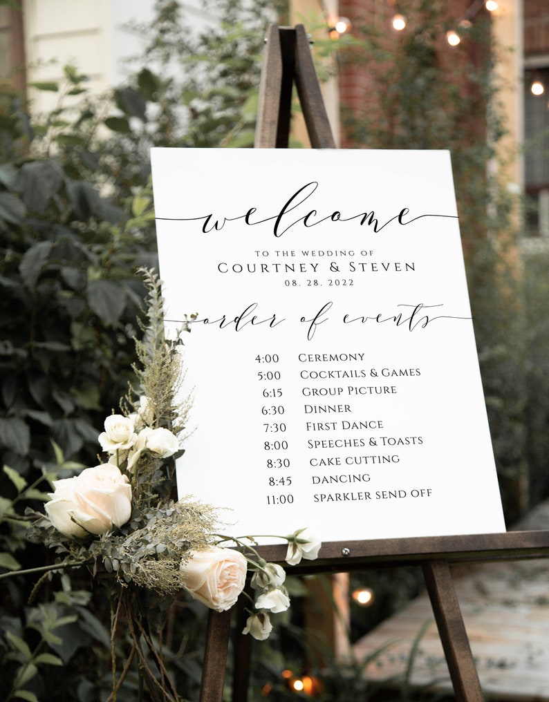 May include: A white wedding welcome sign with black calligraphy text. The sign lists the order of events for the wedding of Courtney and Steven on August 28, 2022. The sign is on an easel.