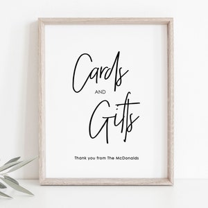 May include: A white framed sign with black calligraphy that reads "Cards and Gifts" with the text "Thank you from The McDonalds" below.
