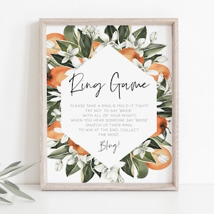 Puede incluir: Un cartel imprimible con un dise&ntilde;o floral con flores de azahar y naranjas. El cartel dice "Ring Game" e incluye instrucciones para un juego en el que los invitados intentan recoger anillos. El texto dice: "&iexcl;Por favor, toma un anillo y suj&eacute;talo bien fuerte! &iexcl;Intenta no decir 'novia' con todas tus fuerzas! Cuando escuches a alguien decir 'novia', arreb&aacute;tale su anillo. Para ganar al final, recoge la mayor cantidad... &iexcl;Bling!"