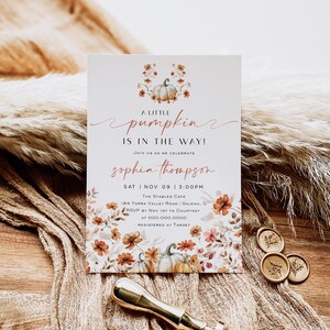 Puede incluir: Una invitación de baby shower blanca y naranja con un diseño de calabaza y flores. El texto dice "A little pumpkin is in the way!" y "Sophia Thompson". La invitación incluye la fecha, la hora, la ubicación, la información de RSVP y los detalles del registro.