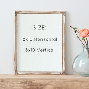 May include: A white wood picture frame with a distressed finish. The frame is sitting on a wooden surface. The text inside the frame reads "SIZE: 8x10 Horizontal 8x10 Vertical".