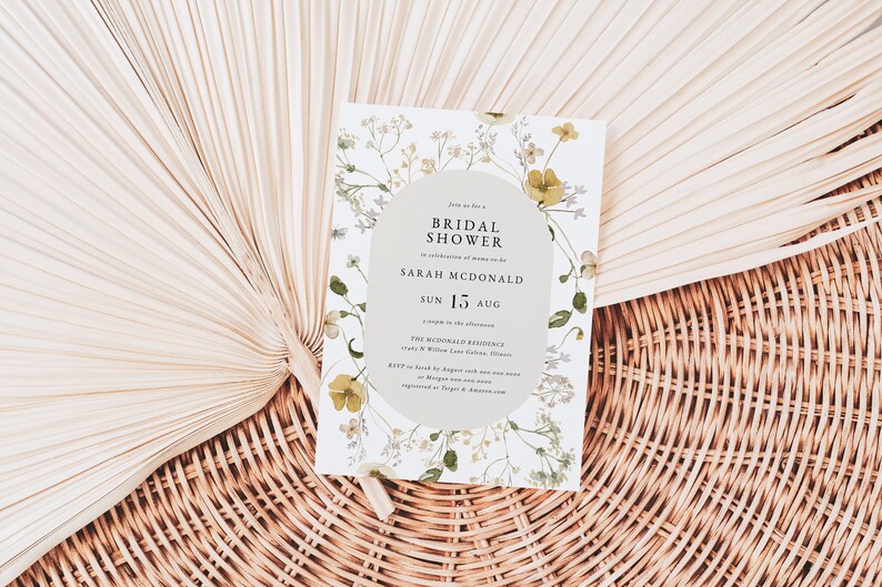 May include: A white floral bridal shower invitation with a light gray circle in the center. The text reads "Join us for a Bridal Shower in celebration of marriage for Sarah McDonald Sun 15 Aug The McDonald Residence 123 N Willow Lane, Gotham, Illinois RSVP by August 1st with your name and number at [email protected] or register at Target & Amazon.com"