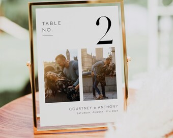 May include: A white table number card with a gold frame, featuring the number "2" in black text. The card also includes the text "TABLE NO." and "COURTNEY & ANTHONY, SATURDAY, AUGUST 17TH 202X". Two photos of a couple are displayed on the card.