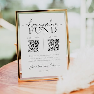 May include: A white sign with black text and a heart symbol reads "honeymoon FUND".  The sign has two QR codes, one for Cash App and one for Venmo.  The text below the QR codes reads "If you had fun and want to give a gift to send us on our way, a donation to our honeymoon fund would really make our day!"  The sign is signed "Annabeth and James" and the date "05. 12. 202X".