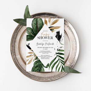 May include: A white baby shower invitation with gold and black accents. The invitation features a diamond shape with the text "Baby Shower" and the name "Brooklyn McDonald". The background features a watercolor design of tropical leaves and gold accents.