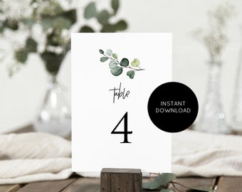 May include: White table number card with a green watercolor eucalyptus branch design. The card says "Table 4" in black text.