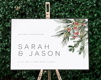 May include: A white wedding sign with a watercolor illustration of pine branches and red berries. The sign reads "Welcome to our wedding", "Sarah & Jason", "12. 15. 20XX | Apple River, Illinois".